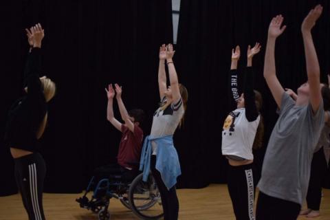 Five people raising arms within a dance session 