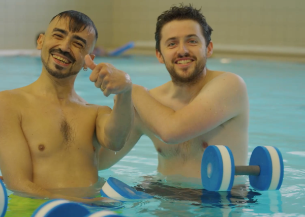 Two people in the water, one with their thumb up and smiling