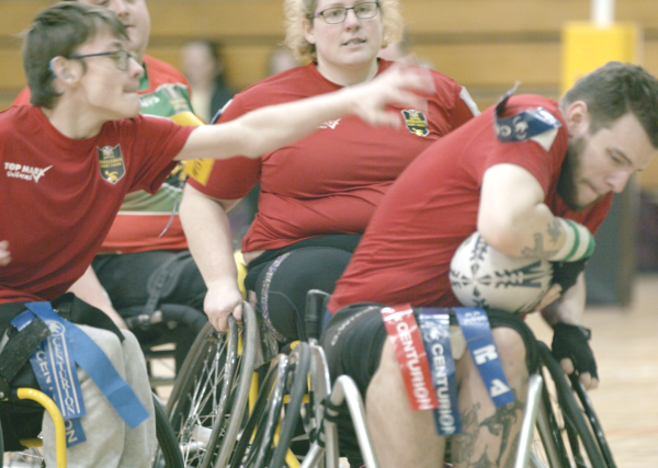2 wheelchair rugby league players, 1 attempting a tackle and the other ducking with the ball