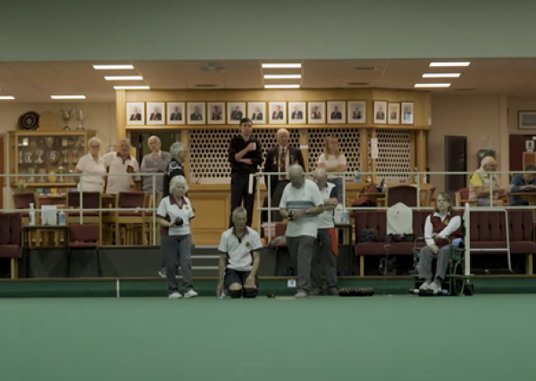 Group of disabled and non-disabled people getting ready to play bowls at an indoor rink. 